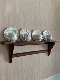 there are five tea cups and saucers on the shelf