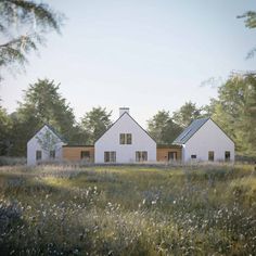 two white houses sitting in the middle of a field with tall grass and trees around them