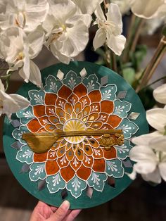 a person holding a decorative plate with flowers in the background