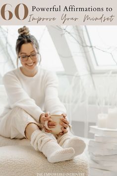 a woman sitting on top of a bed holding a cup