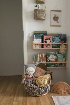 there is a stuffed animal in a basket on the floor next to a bookshelf