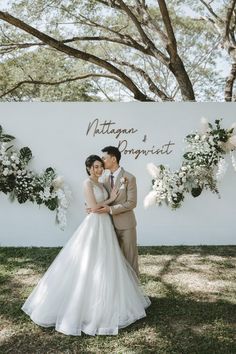 a newly married couple standing in front of a sign