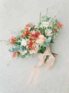 a bouquet of flowers is tied up on the ground with a bow around it's neck