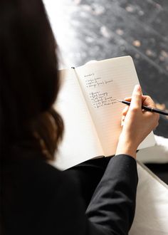 a woman writing on a notebook with a pen