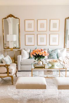 a living room filled with white furniture and lots of pictures on the wall above it