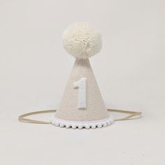 a white hat with a number one on it and pom - poms around the top