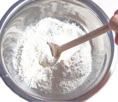 a wooden spoon in a glass bowl filled with flour