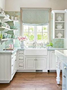 a kitchen filled with lots of white cabinets and counter top space next to a window