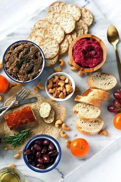 an assortment of food is displayed on a marble counter top with bread, olives, and other foodstuffs