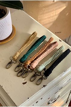 six pairs of key chains sitting on top of a white table next to a potted plant