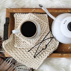 a cup of coffee on top of a knitted blanket