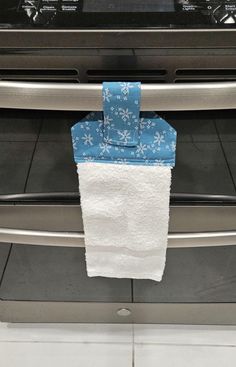 a white towel hanging from the handle of an oven with blue and white flowers on it