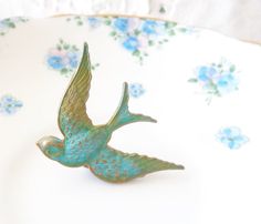 a blue bird brooch sitting on top of a white and blue flowered plate