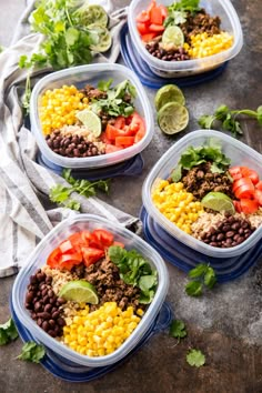 four plastic containers filled with mexican food on top of a wooden table next to cilantro and lime wedges