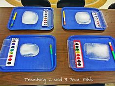 four ice painting trays on a table with pencils and watercolor paints in them