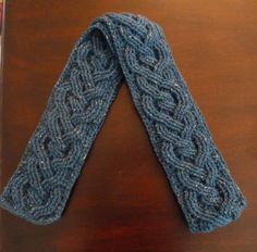 a blue knitted tie sitting on top of a wooden table