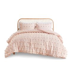 a bed with pink comforter and pillows on it's side, in front of a white background