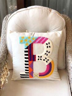 a white chair with a pillow that has the letter b on it and is decorated in bright colors