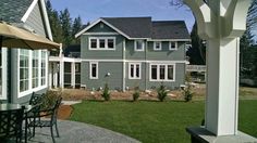 a gray house with white trim on the windows and doors is seen through an open patio door