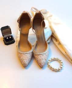 a pair of white shoes and pearls are on the table next to a napkin, ring, and bracelet