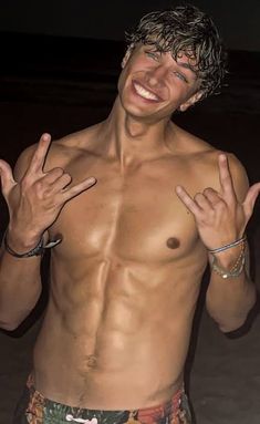 a shirtless man with his hands in the air and one hand out, smiling