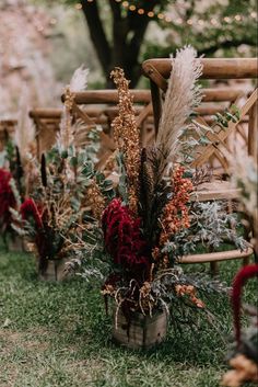 an outdoor ceremony set up with wooden chairs and flowers on the grass, surrounded by string lights