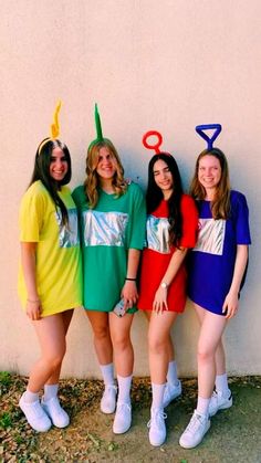 four girls are dressed up in costumes and standing next to a wall