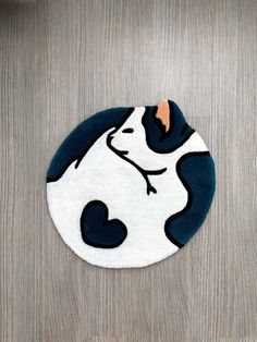 a black and white cat rug sitting on top of a wooden floor next to a wall