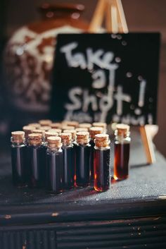 there are bottles of syrup sitting on the table next to a chalkboard sign that says take it shot