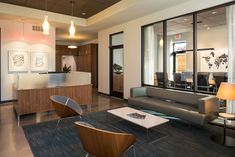 an office lobby with couches, chairs and desks in front of large windows