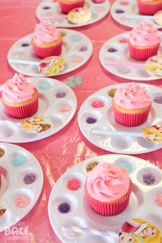 many cupcakes are on plates with pink frosting