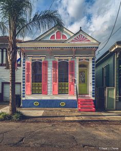 a colorful house with red shutters and palm trees