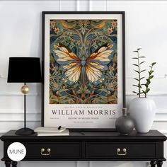 a black table topped with a lamp next to a framed butterfly art print on the wall