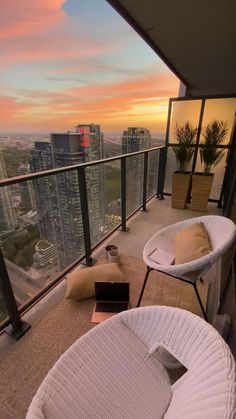 a balcony with two chairs and a laptop on the table in front of cityscape