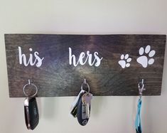 a wooden sign with key hooks hanging from it's sides that says, his hers