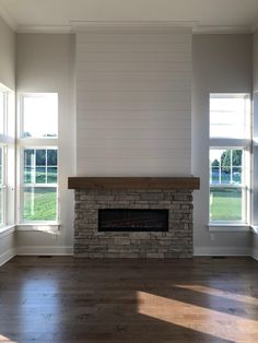 an empty living room with two windows and a fireplace in the middle of the room