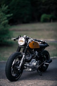 a black and brown motorcycle parked on the side of a road with trees in the background