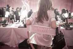 a woman holding up a victoria's secret sign in front of a room full of people