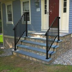 a set of stairs leading to the front door of a house with stone steps and handrails