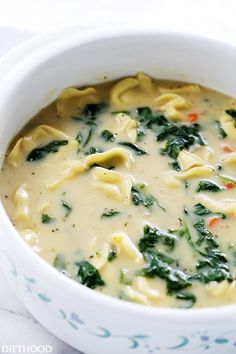 a white bowl filled with pasta and spinach