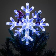 an illuminated snowflake ornament on a christmas tree with two gnomes