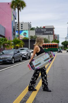 a woman is walking down the street with her skateboard in hand and carrying it