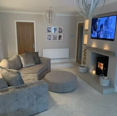 a living room filled with furniture and a flat screen tv mounted on the wall above a fire place