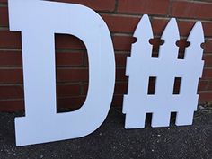 the letters d and person are made out of white plywood wood, along with a brick wall