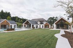 a row of houses sitting on top of a lush green field next to a swimming pool