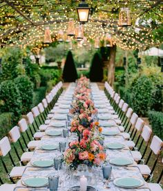 a long table is set with plates and place settings for an outdoor dinner party in the garden