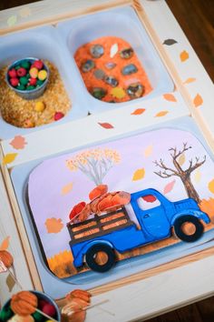 a blue truck with pumpkins in the back is sitting on top of a table