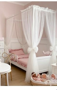 a white canopy bed sitting next to a table with stuffed animals on top of it