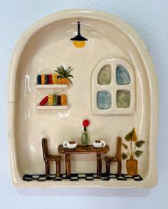 a ceramic wall hanging with a table and chairs