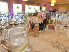 the table is set with wine glasses, silverware and menu cards for an event